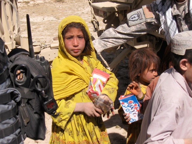 A local girl holding some sandals and a beanie baby she received from one of your care packages.