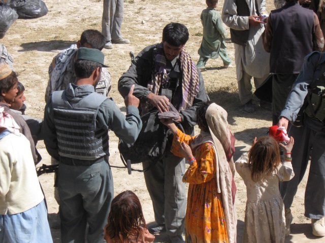 An Afghan Police Officer giving a young girl a pair of mittens we found in one of our care packages.